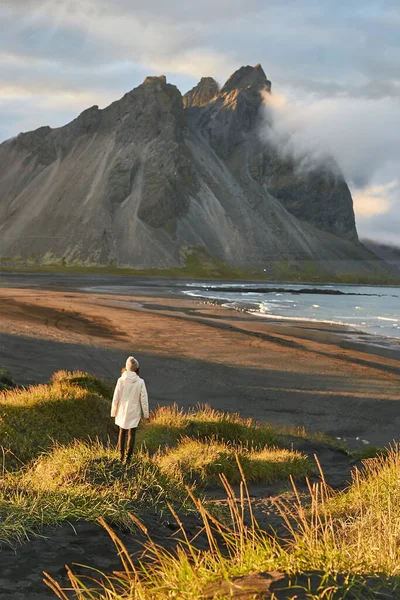 Woman enjoying amazing landscape at Stokksnes. Rear view of female tourist looking at famous Vestrahorn mountains in Iceland