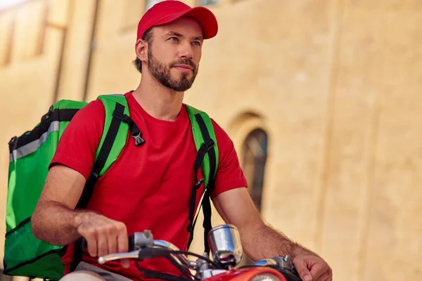 Portrait of young caucasian delivery man on scooter
