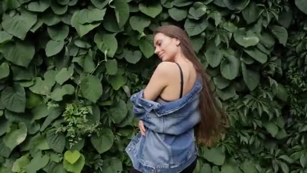 ジーンズのジャケットと公園を歩いて長い髪の美しい若い女性 — ストック動画