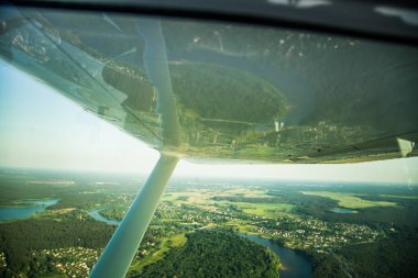 Güzel bir aero manzara kanatları altına küçük uçak pencereden dışarı bakıyor. Riga, Letonya, Avrupa'da yaz. Güneşli, puslu bir gün otantik uçan deneyimi. Havadan manzara.