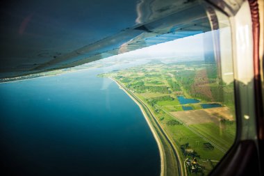 Güzel bir aero manzara kanatları altına küçük uçak pencereden dışarı bakıyor. Riga, Letonya, Avrupa'da yaz. Güneşli, puslu bir gün otantik uçan deneyimi. Havadan manzara.