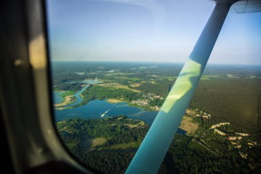 Güzel bir aero manzara kanatları altına küçük uçak pencereden dışarı bakıyor. Riga, Letonya, Avrupa'da yaz. Güneşli, puslu bir gün otantik uçan deneyimi. Havadan manzara.