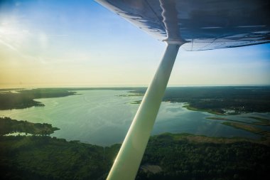 Güzel bir aero manzara kanatları altına küçük uçak pencereden dışarı bakıyor. Riga, Letonya, Avrupa'da yaz. Güneşli, puslu bir gün otantik uçan deneyimi. Havadan manzara.