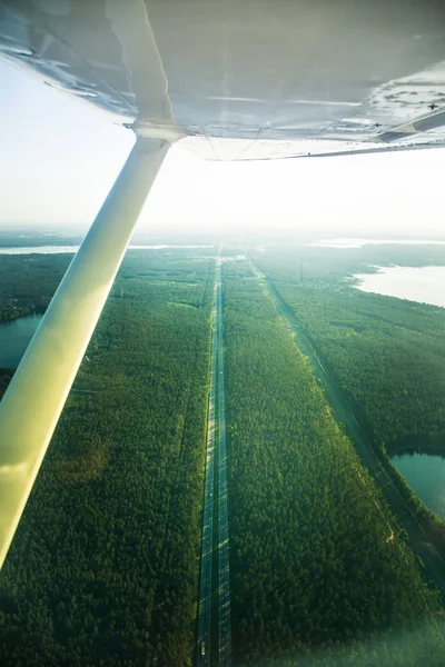 A beautiful aero landscape looking out of a small plane window under the wing. Riga, Latvia, Europe in summer. Authentic flying experience in a sunny, hazy day. Landscape from air.