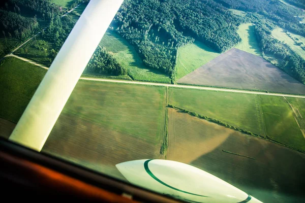 A beautiful aero landscape looking out of a small plane window under the wing. Riga, Latvia, Europe in summer. Authentic flying experience in a sunny, hazy day. Landscape from air.