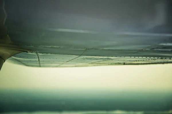 A beautiful aero landscape looking out of a small plane window under the wing. Riga, Latvia, Europe in summer. Authentic flying experience in a sunny, hazy day. Landscape from air.