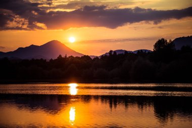 Dağlar, göl ve orman mor tonlarda üzerinde güzel, renkli bir günbatımı. Soyut, parlak manzara. Tatra Dağları Slovakya, Europe.