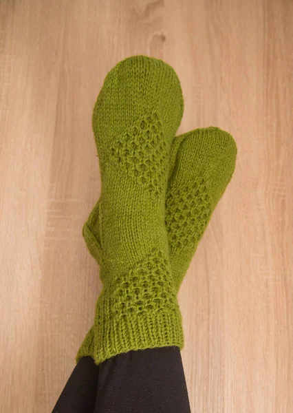 A woman wearing warm hand craft socks. Knitted form a natural sheep wool yarn. Winter clothing. On a wooden background.