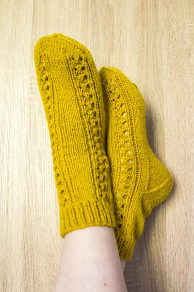 A woman wearing warm hand craft socks. Knitted form a natural sheep wool yarn. Winter clothing. On a wooden background.