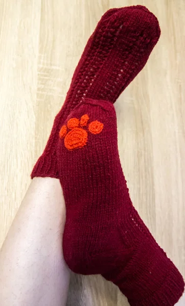 A woman wearing warm hand craft socks. Knitted form a natural sheep wool yarn. Winter clothing. On a wooden background.