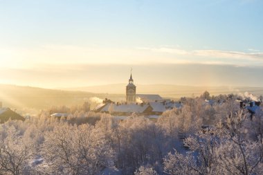 Küçük Norveç kasabası Roros'ta güzel gün batımı. Akşam güneşinde kilise. İskandinav kış manzarası.