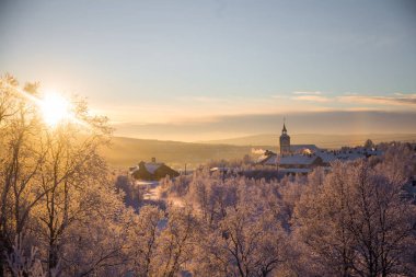 Küçük Norveç kasabası Roros'ta güzel gün batımı. Akşam güneşinde kilise. İskandinav kış manzarası.