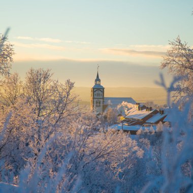 Küçük Norveç kasabası Roros'ta güzel gün batımı. Akşam güneşinde kilise. İskandinav kış manzarası.