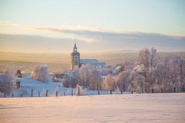 Küçük Norveç kasabası Roros'ta güzel gün batımı. Akşam güneşinde kilise. İskandinav kış manzarası.