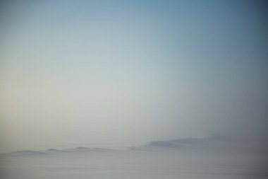 Kışın Norveç tepelerinde güzel, sisli bir sabah. Beyaz, puslu manzara. Küçük Norveç kasabası Roros yakınlarında.