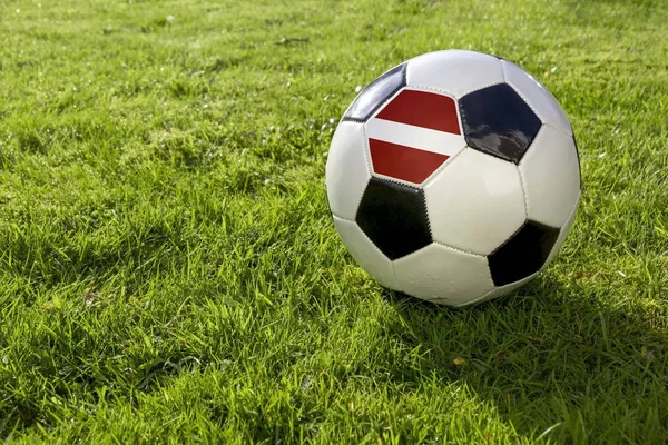 在草地上的足球与拉脱维亚国旗 — 图库照片