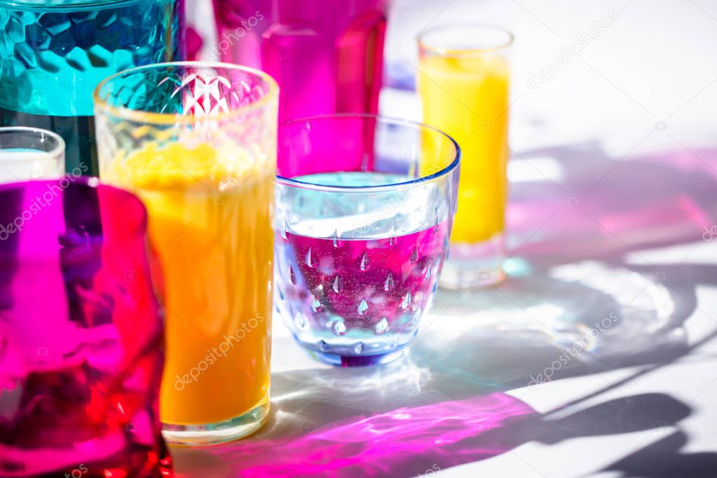 Glass goblets create wonderful coloured shadows on a solar table. The shadow of sunlight reflect to glass of pink and yellow, emerald colors.
