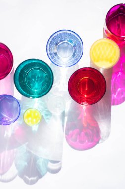 Cam kadehler bir güneş masa üzerinde harika renkli gölgeler oluşturun. Güneş ışığının gölgesi pembe ve sarı, zümrüt renklerin cam yansıtır. Üstte görüntü.