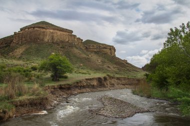 Güneşli bir yaz günü Alp gölünde, ağaçlar, çimenler ve çalılar dağların yamaçlarında yetişir, gökyüzü sudaki dağlar ve ağaçları yansıtır, bulutsuz berrak mavi gökyüzü, uzak yamaçlarda evler vardır.
