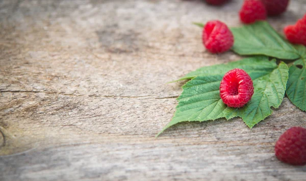 ahşap backg üzerinde bir saçılma Ahududu ve Ahududu yaprakları