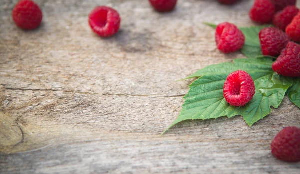 ahşap backg üzerinde bir saçılma Ahududu ve Ahududu yaprakları