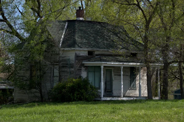 Güzel terk edilmiş çiftlik ev ağaçların arasında ihmal oturur 