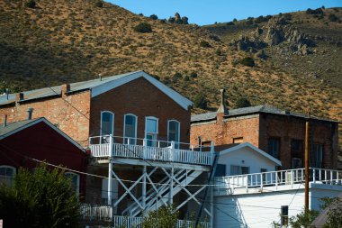 Virginia City, Nevada 'daki tarihi binaların tepelerine bakıyorum. Arka plandaki kayalık dağlara.