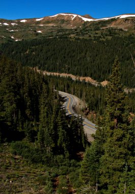 Bir dağ geçidinden aşağıya, bir otobana bakıyor. Manzaraya doğru ilerliyor.