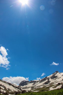 Mavi gökyüzü, bulutlar, Lago Naki Platosu, Rusya, Batı Kafkasya, Adygea Cumhuriyeti. Dağlar, doğa, bahar, kar, köknar ağaçları, çamlar