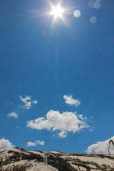 Mavi gökyüzü, bulutlar, Lago Naki Platosu, Rusya, Batı Kafkasya, Adygea Cumhuriyeti. Dağlar, doğa, bahar, kar, köknar ağaçları, çamlar