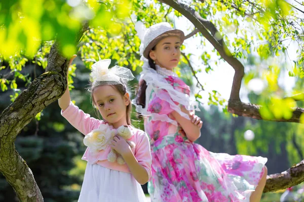 The little girl turned away from her mother, smiles and flirts, shows character. Mom sits and upset on the very colorful tree. Mother and daughter in a summer park.