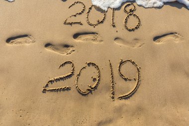 Mutlu yeni yıl 2019 kavramı geliyor ve 2018 yıl bırakarak. Metin deniz plaj ve kum üzerinde ayak izleri. Basamak yazıt kapsayan su salla. Bir tropik tatil Tayland karşılamak.