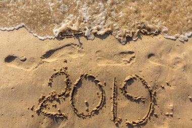 Mutlu yeni yıl 2019 kavramı geliyor ve 2018 yıl bırakarak. Metin deniz plaj ve kum üzerinde ayak izleri. Basamak yazıt kapsayan su salla. Bir tropik tatil Tayland karşılamak.