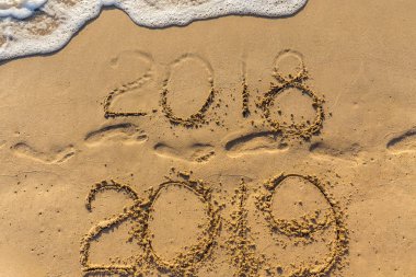 Mutlu yeni yıl 2019 kavramı geliyor ve 2018 yıl bırakarak. Metin deniz plaj ve kum üzerinde ayak izleri. Basamak yazıt kapsayan su salla. Bir tropik tatil Tayland karşılamak.