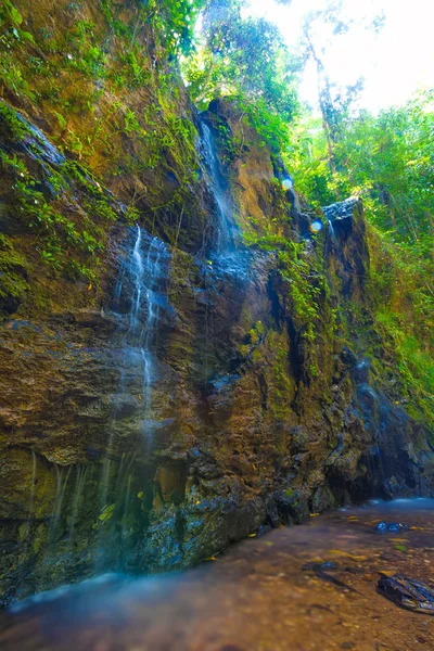 Şelale üzerinde dik yüksek uçurumdan yağmur ormanları, mavi su kahverengi taş çalılıkları içinde. Vahşi orman Lanta Island, Krabi, Tayland.