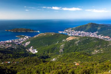 Dağları panoraması ile modern bir Avrupa şehri temiz bulutsuz bir günde mavi Adriyatik Denizi kıyısında yeşil orman kaplı. Becici, Karadağ ve Budva havadan görünümü.