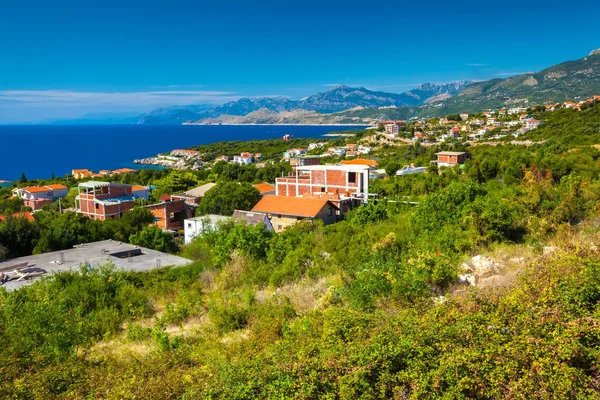 日当たりの良い夏の日に壮大な山々 を背に青いアドリア海の美しい緑の海岸地平線上のレンガの家します 高速道路 ウルツィニ モンテネグロからの眺め — ストック写真