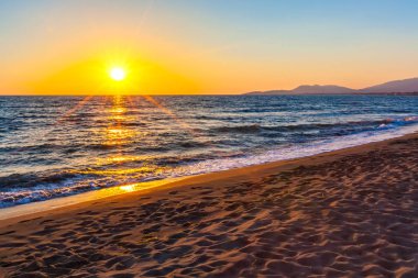 Adriyatik Denizi, güneş ışınlarının parlak renkli turuncu günbatımı altın dalgalarda aydınlatmak ve kıyı boyunca yumuşak ışık dağılım. Kumsalda Ada Bojana, Ulcinj, Karadağ.