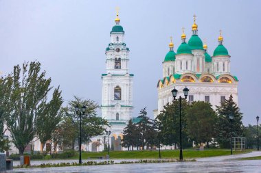 Kutsal Bakire Meryem Varsayım katedral beyaz Hıristiyan Kilisesi, park'ın patika üzerinde sokak lâmbası direği karşısında ağır yağmur altında. Tarihi ve mimari karmaşık Astrakhan Kremlin, Rusya Federasyonu.