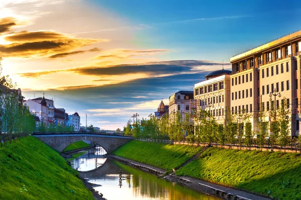 Bulak duct, Kazan, Tatarstan, Rusko. Malá městská řeka, mezi městskými domy, s travnatým zeleným svahem ozářeným zapadajícím sluncem Royalty Free Stock Obrázky