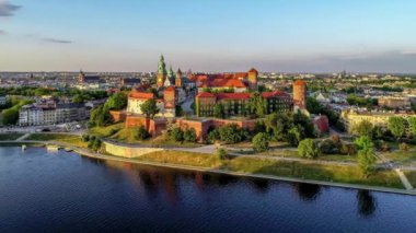 Krakow, Polonya. Wawel royal Castle ve Katedrali, Vistula Nehri, park, gezinti ve yürüyüş insanlar. Cracow içinde belgili tanımlık geçmiş tarihi kiliseler ile eski şehir. Hava 4k video günbatımında baharda yaklaşım