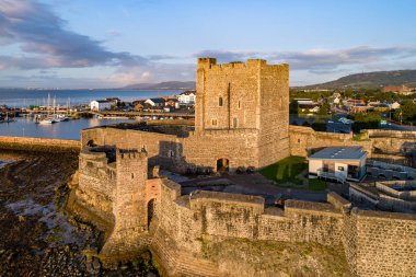 Carrickfergus gündoğumu ışık Belfast yakınındaki Ortaçağ Norman kalesi. Marina, yatlar, Otopark, kasaba ve uzak Belfast görünümünde arka plan ile havadan görünümü
