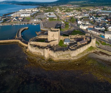 Carrickfergus gündoğumu ışık Belfast yakınındaki Ortaçağ Norman Kalesi. Marina, yatlar, otopark, dalgakıran ve çökeller ile havadan görünümü 