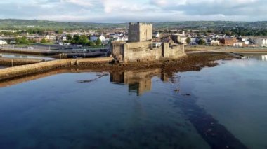 Ortaçağ Norman Kalesi ve gündoğumu ışığında Belfast yakınlarındaki Carrickfergus liman. Su yansıması liman, marina, dalgakıran ve kasaba ile Hava 4k flyby video