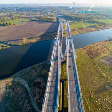 Polonya 'nın Krakow kentindeki Vistula Nehri üzerinde üç şeritli geniş yolları olan yeni modern çift kablolu köprü. Krakow çevresindeki çevre yolunun bir parçası. Hava görüntüsü. Arka planda Sedzimir Çelik Fabrikası