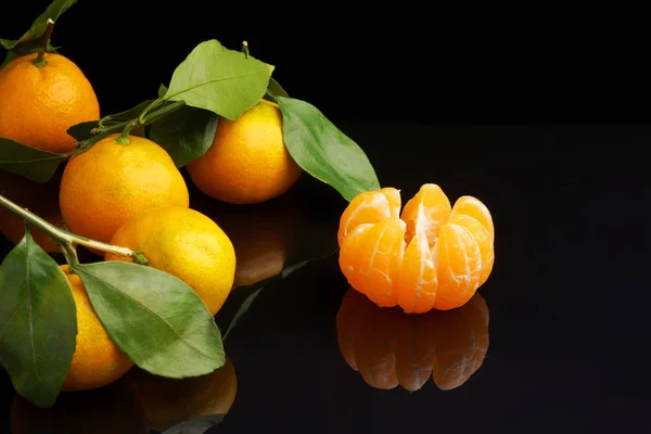 Orange tangerines with leaves on a black background, new year — Stock Photo, Image