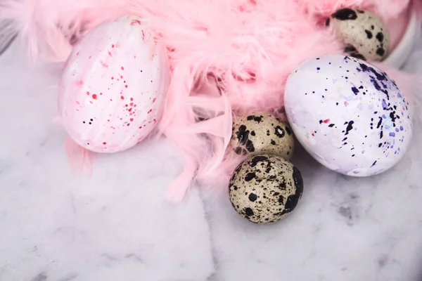 Easter background with Easter eggs and pink feathers. The view from the top. Quail egg