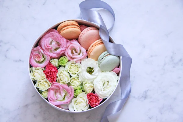 Кругла коробка з квітами та мигдалевим печивом на мармуровому фоні — стокове фото