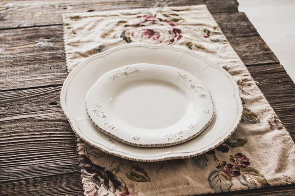 Dos platos vacíos sobre una mesa de madera sobre una servilleta con flores — Foto de Stock