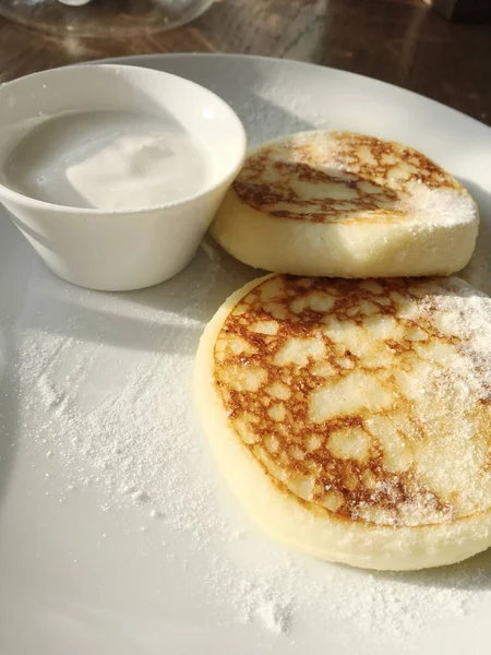 Ricotta pancakes, cottage cheese pancakes on a white plate with sour cream
